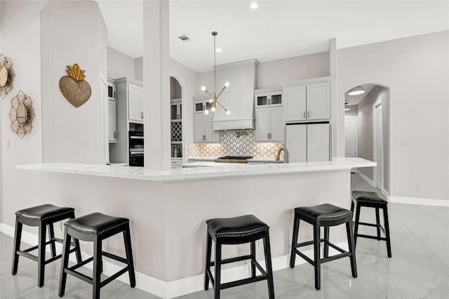 kitchen with a breakfast bar area, decorative light fixtures, kitchen peninsula, white fridge, and decorative backsplash