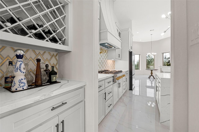 bar with white cabinetry, light stone countertops, black fridge, decorative light fixtures, and stainless steel gas stovetop