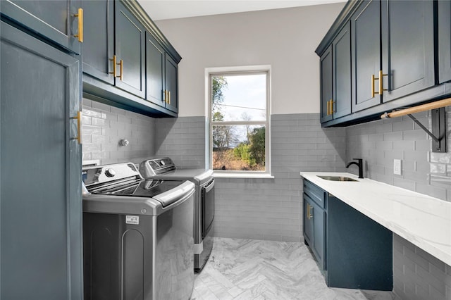 washroom featuring cabinets, sink, tile walls, and washer and clothes dryer