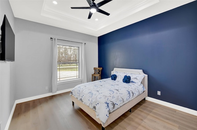 bedroom with hardwood / wood-style floors, a tray ceiling, and ceiling fan