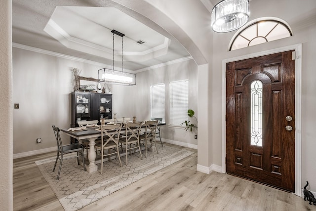 foyer entrance with a raised ceiling, light wood-type flooring, and ornamental molding