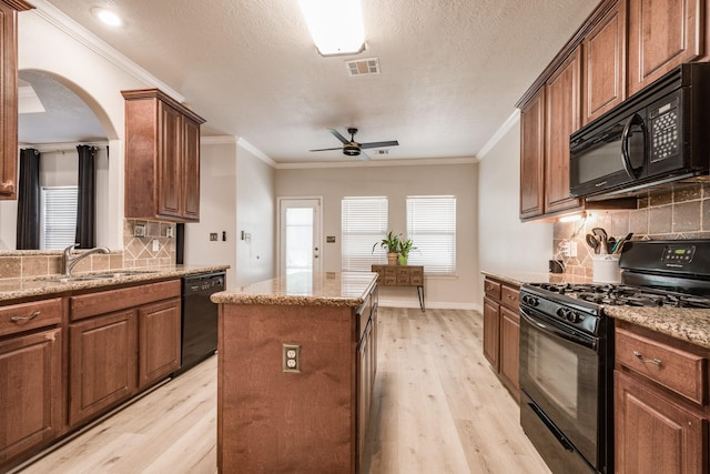 kitchen with black appliances, light wood-type flooring, a center island, and sink