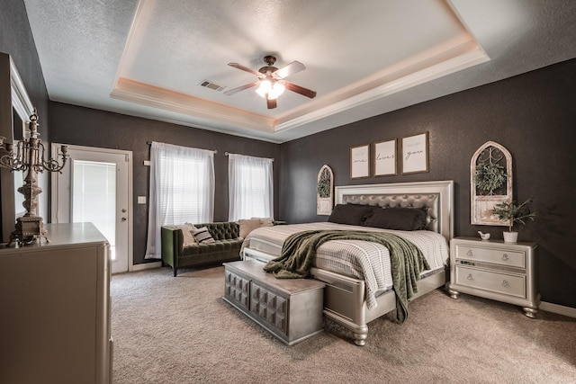 carpeted bedroom with ceiling fan, a raised ceiling, and a textured ceiling