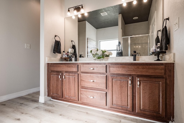 bathroom with hardwood / wood-style flooring, walk in shower, and vanity