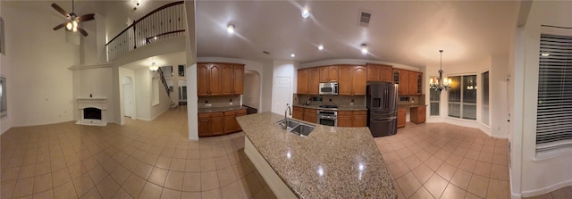 kitchen with sink, decorative light fixtures, a large fireplace, light tile patterned floors, and appliances with stainless steel finishes