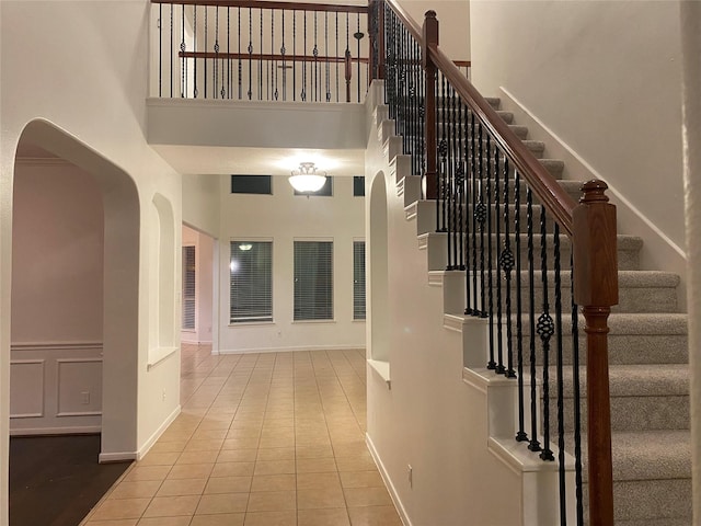 stairway featuring a high ceiling and tile patterned flooring