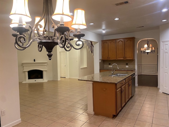 kitchen with sink, stone countertops, light tile patterned floors, and a notable chandelier