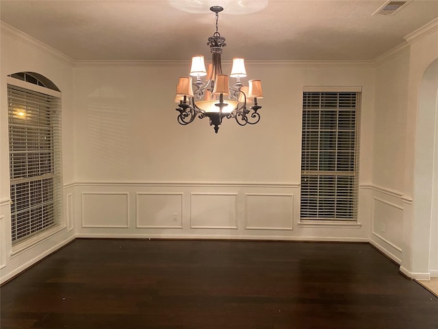 unfurnished dining area with a notable chandelier, dark wood-type flooring, and ornamental molding