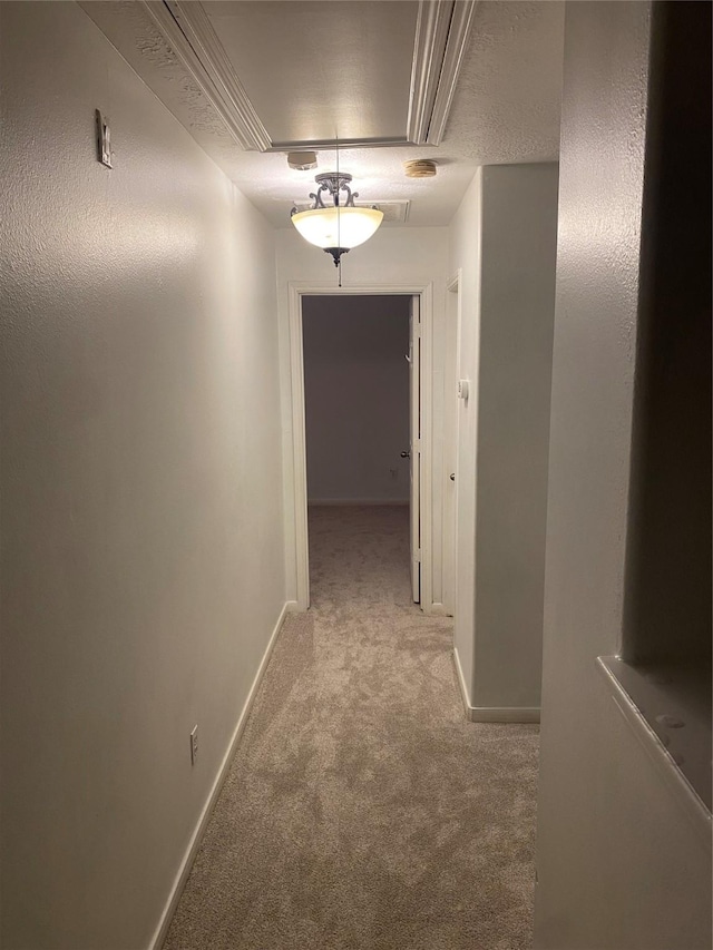 hall with light colored carpet and a textured ceiling