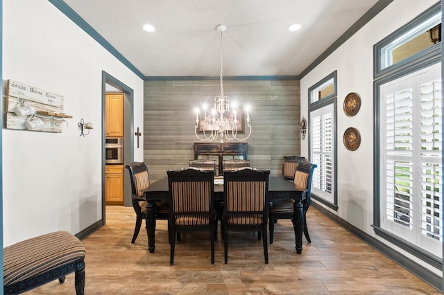 dining room with ornamental molding, a healthy amount of sunlight, a notable chandelier, and wood-type flooring