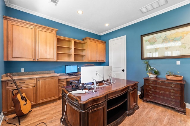 office space with built in desk, light wood-type flooring, and ornamental molding