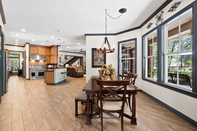 dining space with ceiling fan with notable chandelier, ornamental molding, and light hardwood / wood-style floors