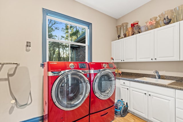 clothes washing area with sink, cabinets, light wood-type flooring, and washer and dryer