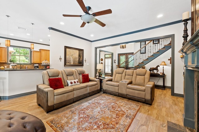 living room featuring light hardwood / wood-style floors, ceiling fan, and crown molding