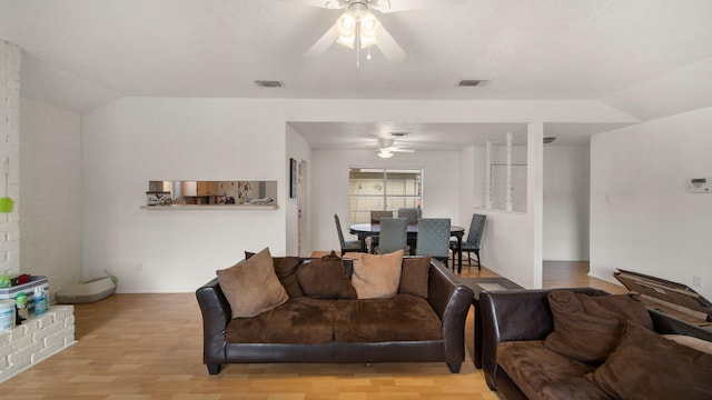 living room with lofted ceiling, ceiling fan, and light hardwood / wood-style flooring