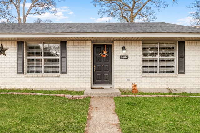 view of exterior entry featuring a lawn