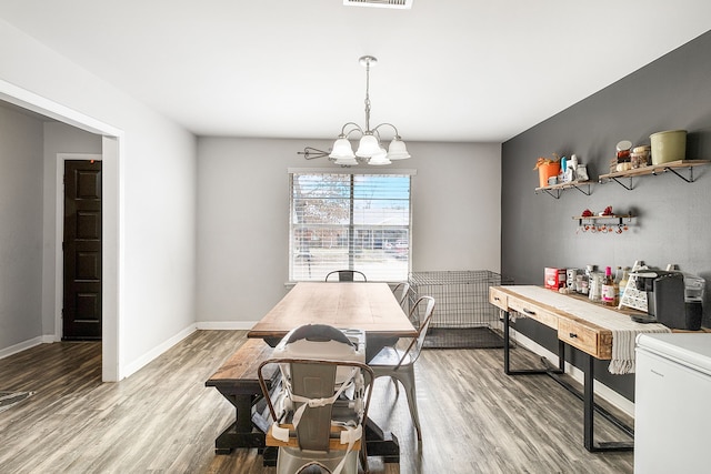 dining area with hardwood / wood-style flooring and a notable chandelier