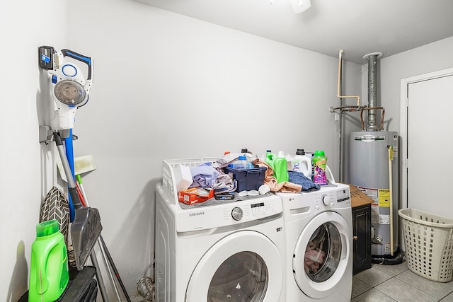 clothes washing area featuring washing machine and dryer, light tile patterned flooring, and gas water heater