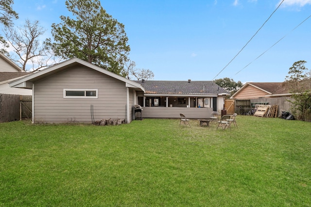 rear view of house featuring an outdoor fire pit and a lawn