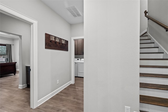 hallway with independent washer and dryer and hardwood / wood-style flooring