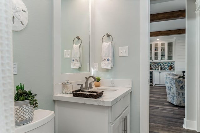 bathroom with tasteful backsplash, beamed ceiling, wine cooler, wood-type flooring, and vanity