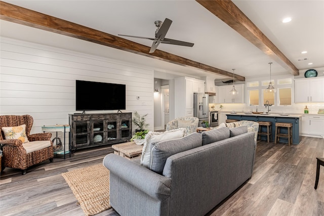 living room with beam ceiling, ceiling fan, wood-type flooring, and wooden walls