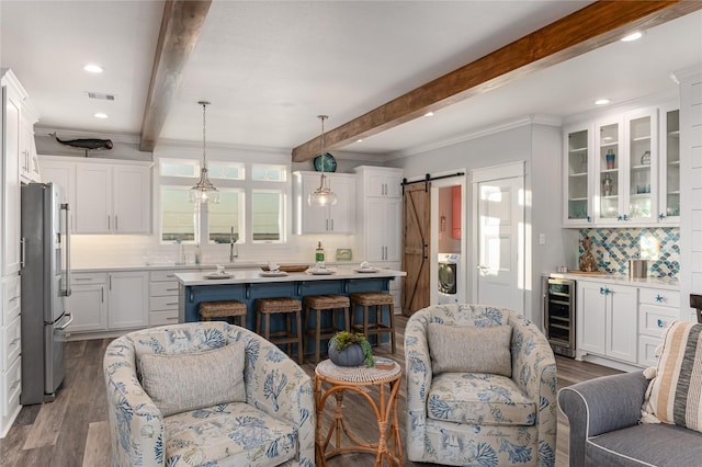 kitchen with hanging light fixtures, wine cooler, a barn door, white cabinetry, and high end fridge