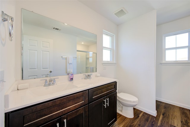 bathroom with walk in shower, hardwood / wood-style flooring, vanity, and toilet