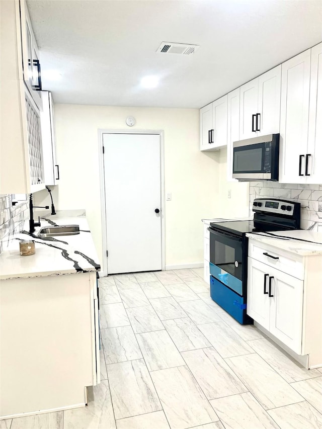 kitchen featuring sink, stainless steel appliances, white cabinetry, and light stone countertops