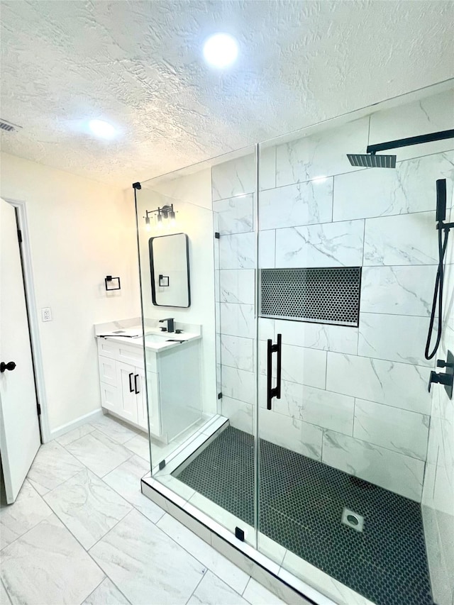 bathroom featuring a textured ceiling, a shower with door, and vanity