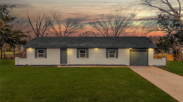 ranch-style house featuring a garage and a lawn