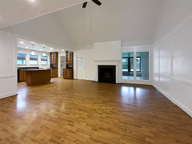 unfurnished living room with high vaulted ceiling, hardwood / wood-style floors, and ceiling fan