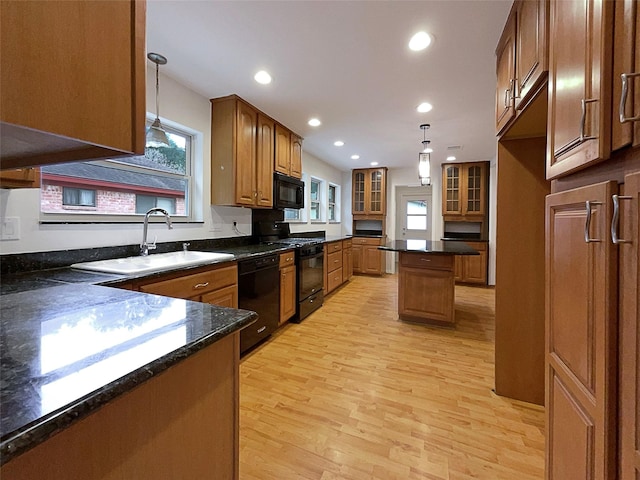 kitchen featuring black appliances, light wood-type flooring, decorative light fixtures, and sink