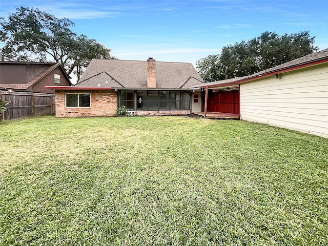 rear view of property with a lawn and a sunroom