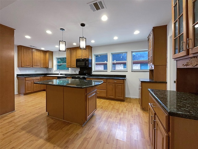 kitchen featuring a center island, light wood-type flooring, range, a wealth of natural light, and pendant lighting