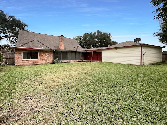 back of property with a lawn and a sunroom