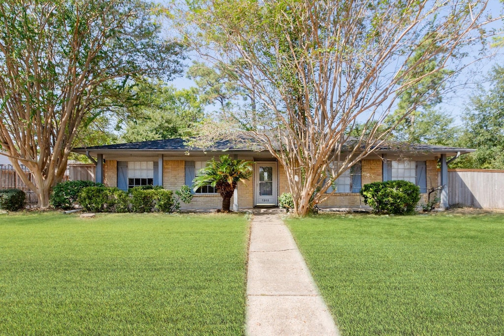 single story home featuring fence, a front lawn, and brick siding