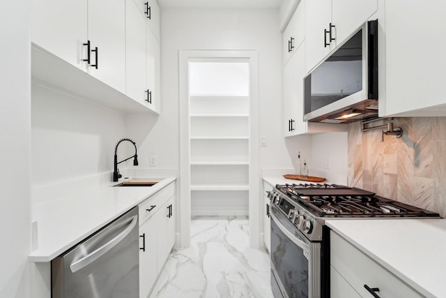 kitchen featuring stainless steel appliances, white cabinetry, backsplash, and sink