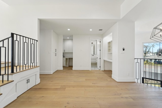 hallway featuring a chandelier and light hardwood / wood-style floors