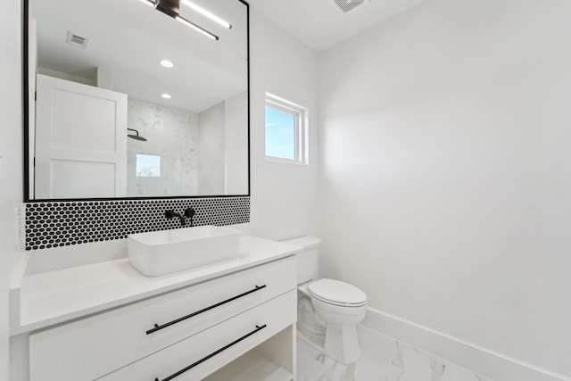 bathroom featuring vanity, tiled shower, toilet, and tasteful backsplash