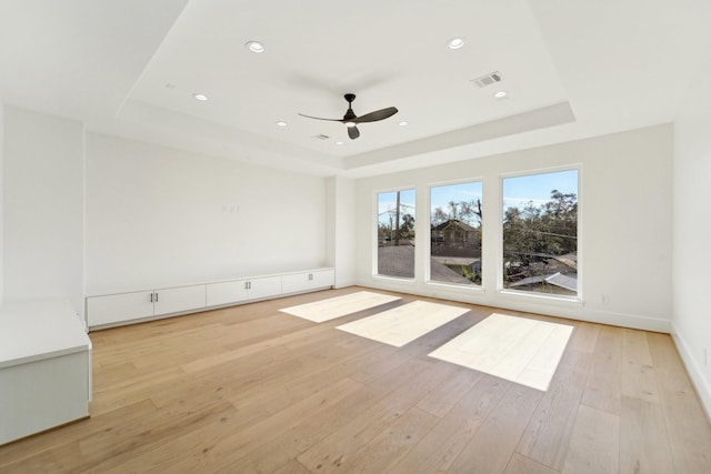 spare room featuring ceiling fan, light hardwood / wood-style flooring, and a tray ceiling