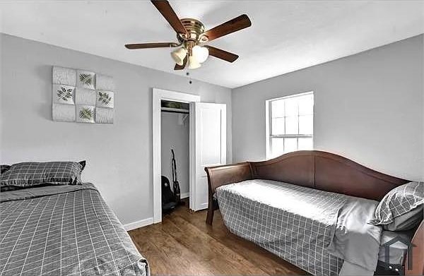 bedroom featuring dark wood-type flooring, a closet, and ceiling fan