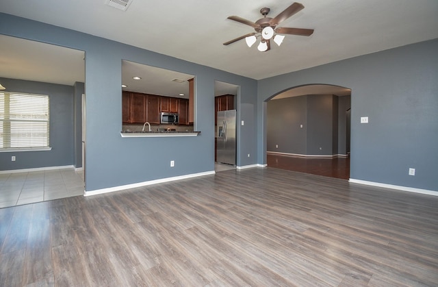 unfurnished living room featuring ceiling fan and dark hardwood / wood-style floors