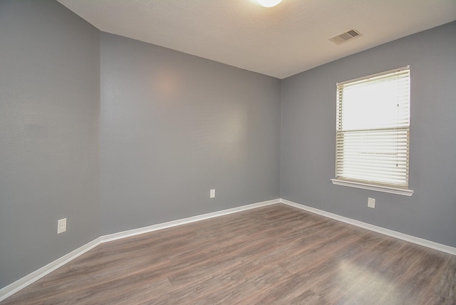 empty room with wood-type flooring and a healthy amount of sunlight