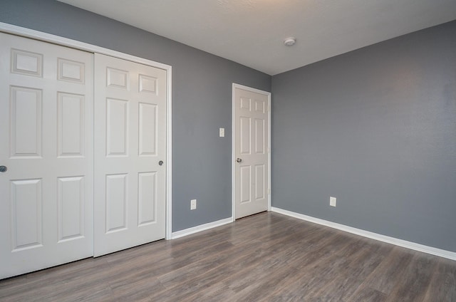 unfurnished bedroom featuring a closet and dark wood-type flooring