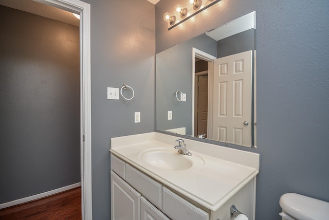 bathroom with hardwood / wood-style floors, vanity, and toilet