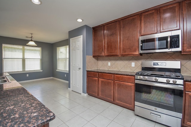 kitchen with stainless steel appliances, sink, light tile patterned floors, decorative backsplash, and hanging light fixtures