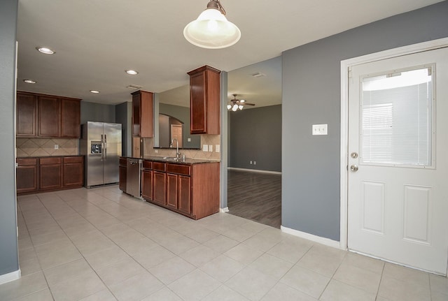 kitchen featuring appliances with stainless steel finishes, pendant lighting, sink, light tile patterned flooring, and tasteful backsplash