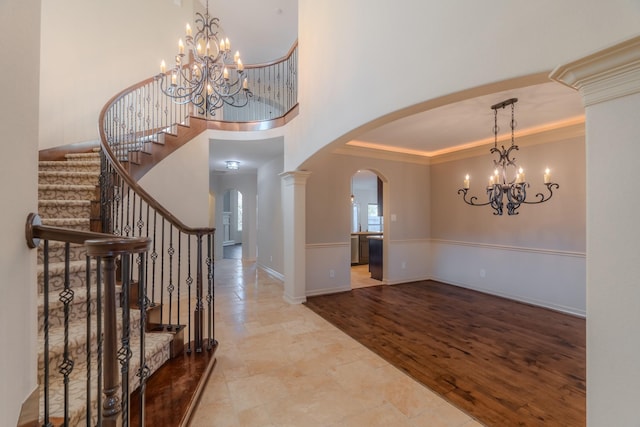 foyer entrance with a notable chandelier, ornamental molding, and ornate columns