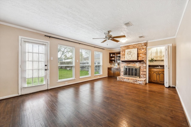 unfurnished living room featuring ceiling fan, dark wood-type flooring, a brick fireplace, a textured ceiling, and sink